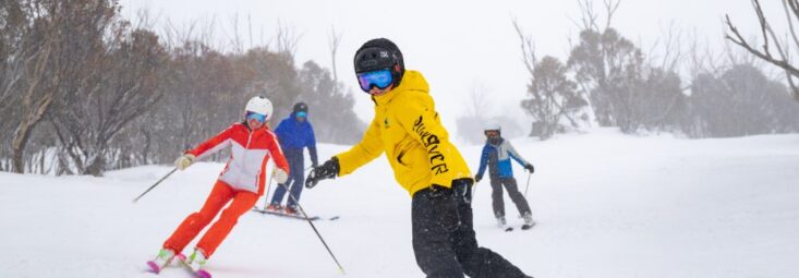 A group skiing and snowboarding at Thredbo Resort