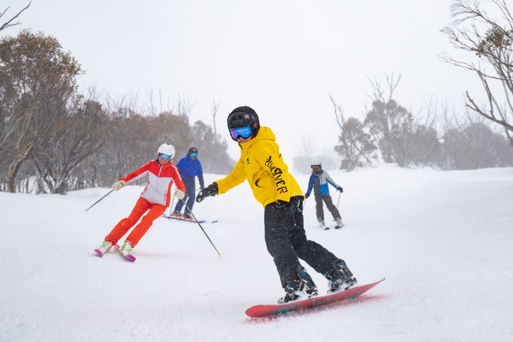 A group skiing and snowboarding at Thredbo Resort